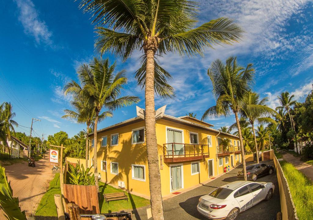 a yellow building with a palm tree in front of it at Pousada Ravenalas - Apartamentos e Flats in Barra Grande