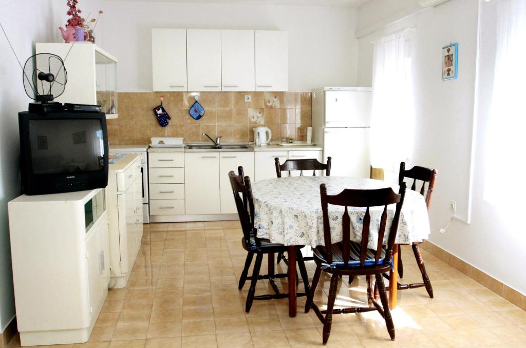 una cucina con tavolo, sedie e TV di Apartman Gordana a Trogir