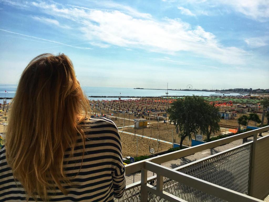 Eine Frau auf einem Balkon mit Blick auf eine Stadt. in der Unterkunft Hotel Tritone Rimini in Rimini