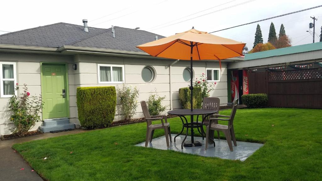 una mesa y sillas con una sombrilla en un patio en Milwaukie Inn Portland South, en Milwaukie