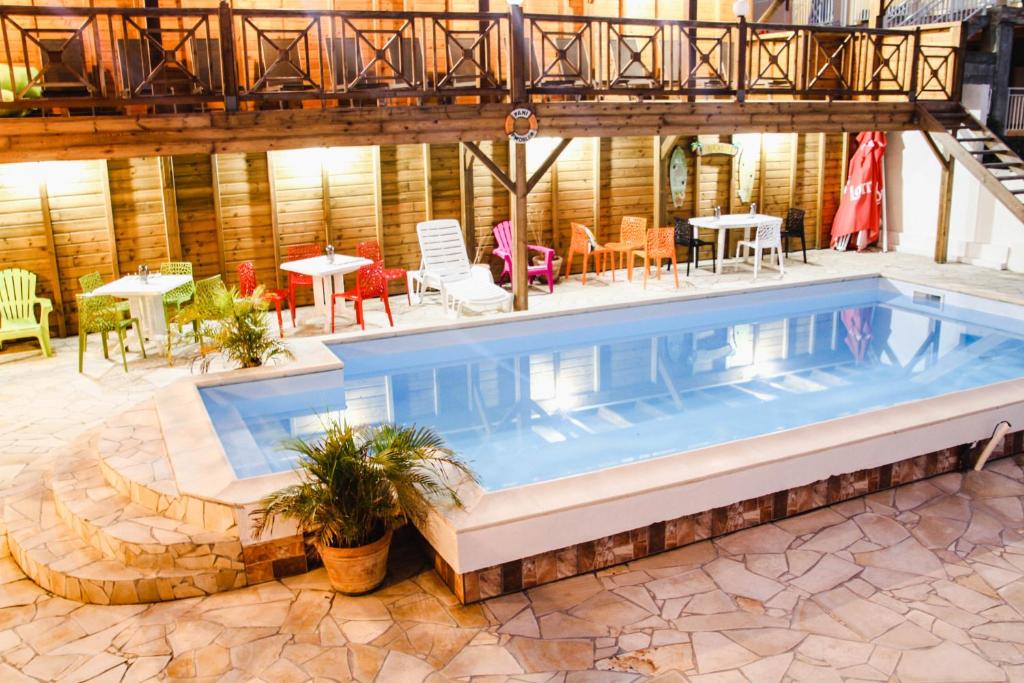 una piscina en un patio con mesas y sillas en Résidence fruit de la passion Caliente, en Sainte-Anne