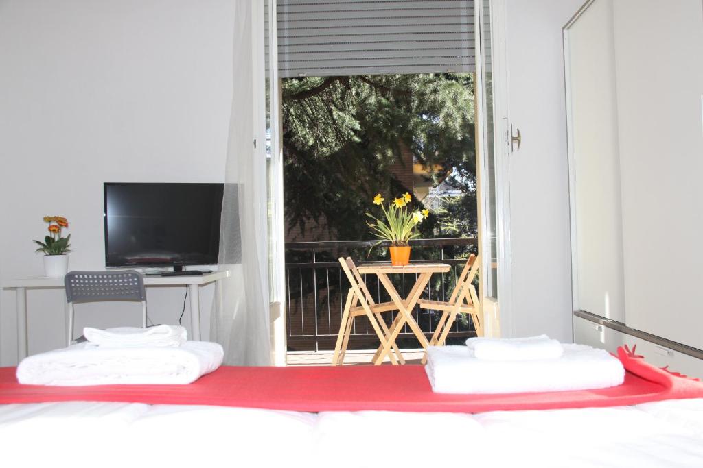 a bedroom with two beds and a tv and a balcony at Lotus B&B in Milan