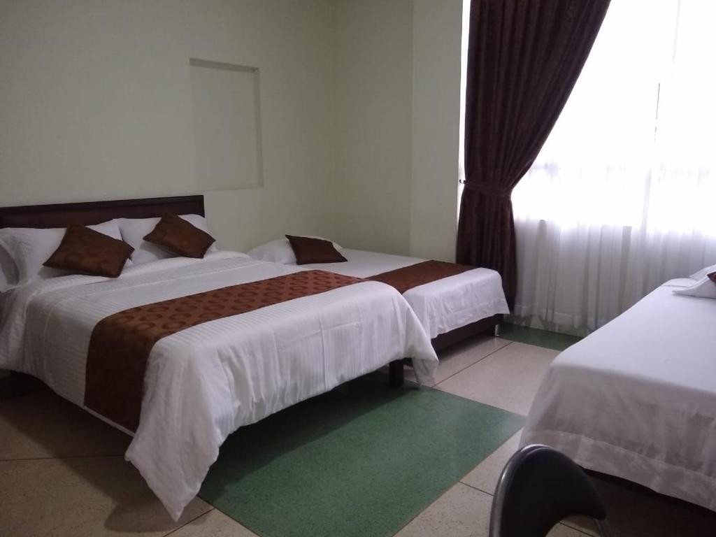 a hotel room with two beds and a window at Hotel Cafetto in Pereira