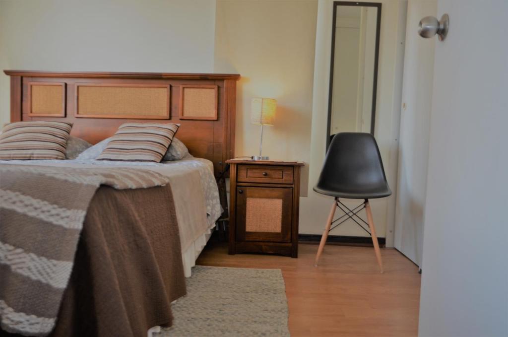 um quarto com uma cama, uma cadeira e uma mesa em Departamentos Amoblados Paz em Santiago