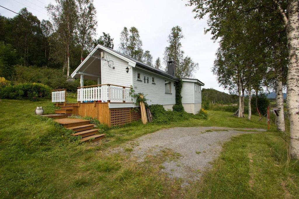 a white house with a porch and stairs at Midt Troms Perle in Finnsnes