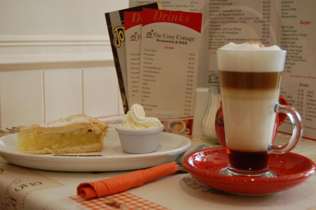 a table with a plate of cake and a drink at The Cosy Cottage in Moville