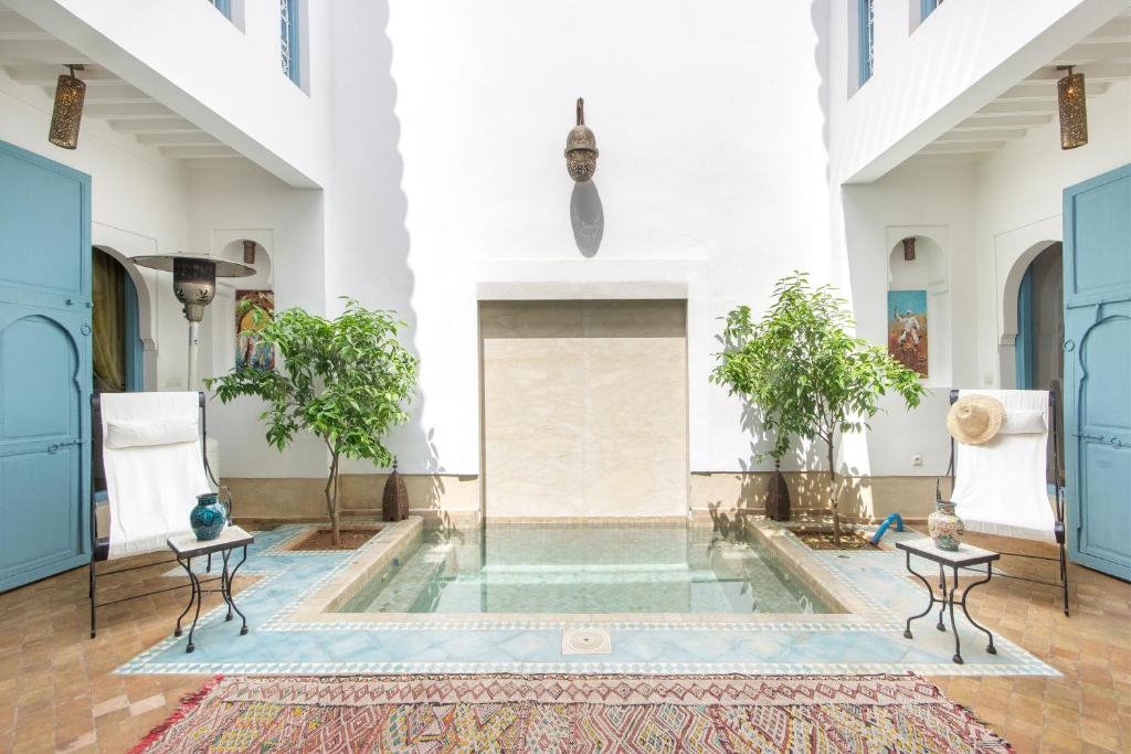 a pool in the middle of a room with two chairs at Riad Ayla avec Piscine Privée in Marrakesh