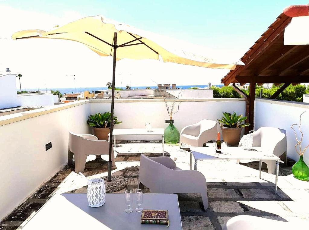 een patio met tafels en stoelen en een parasol bij Salento Calette Apartment in Santa Maria al Bagno