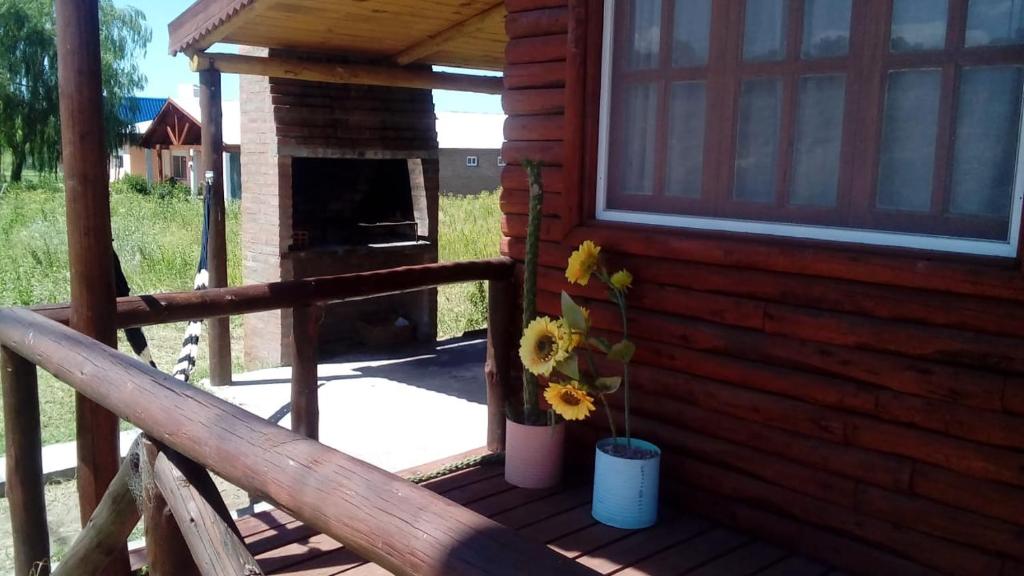 porche de una cabaña de madera con chimenea en Las Huellas Cabaña en 