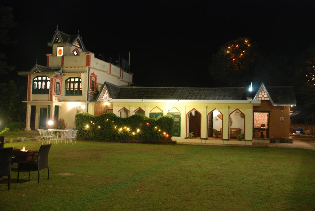 a large white building with christmas lights in the yard at WelcomHeritage Judges Court in Kangra