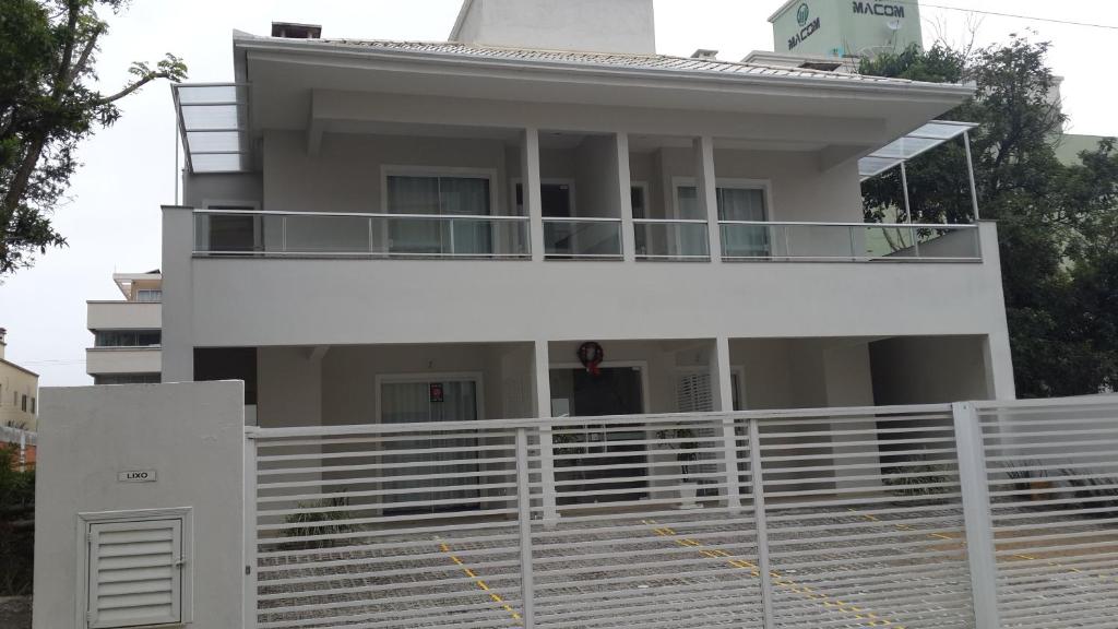 una casa blanca con una valla blanca delante de ella en Apartamentos próximo à praia, en Bombinhas