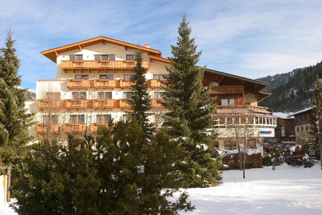 hotel w śniegu z drzewami przed nim w obiekcie Hotel Sportalm w mieście Gerlos
