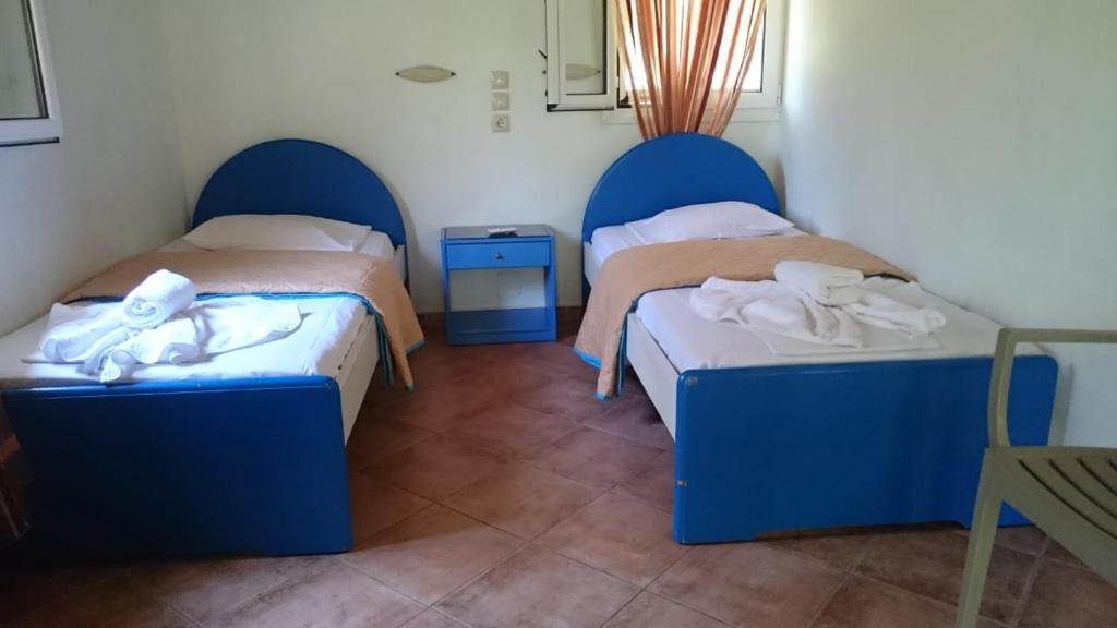duas camas num quarto com cabeceiras azuis em Dakis Studios em Kerion