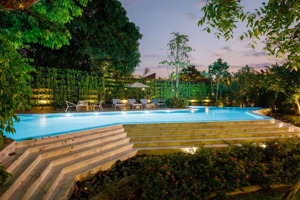 a swimming pool at night with a table and chairs at Parc Borough City Resort in Chiang Mai