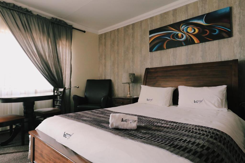 a bedroom with a bed and a desk and a chair at Ledumo Guest lodge in eMalahleni