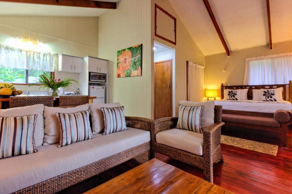 a living room with two beds and wicker chairs at Te Ava Beach Villas in Rarotonga