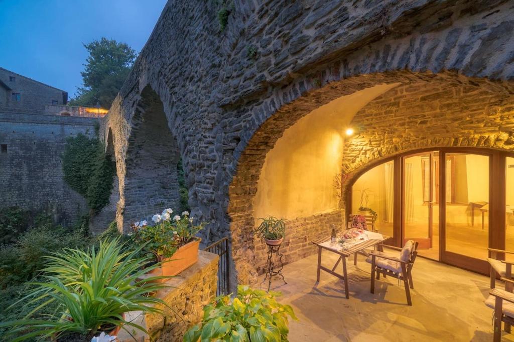 patio con pareti in pietra, tavolo e sedie. di La casa sul ponte a Mercatello sul Metauro