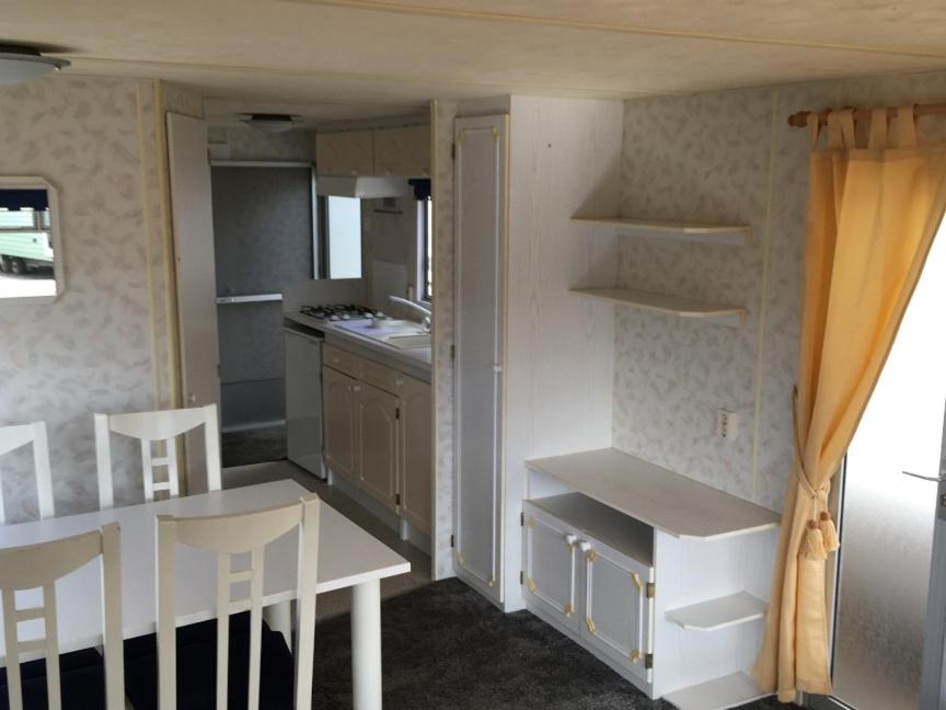 eine kleine Küche mit einem weißen Tisch und Stühlen in der Unterkunft DOMKI HOLENDERSKIE U Borysa in Pobierowo