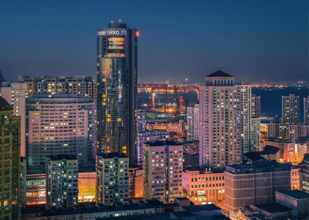 un perfil urbano por la noche con un edificio alto en Hotel Nikko Dalian, en Dalian
