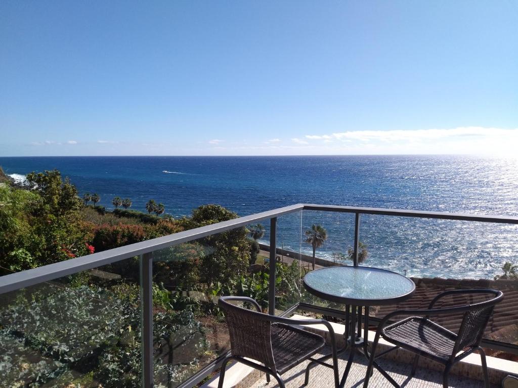 a balcony with a table and chairs and the ocean at Casa do Calhau in Jardim do Mar