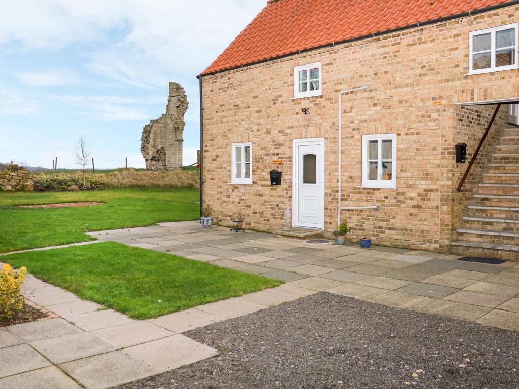 a brick house with a white door and a yard at Carrington Cottage in Lincoln