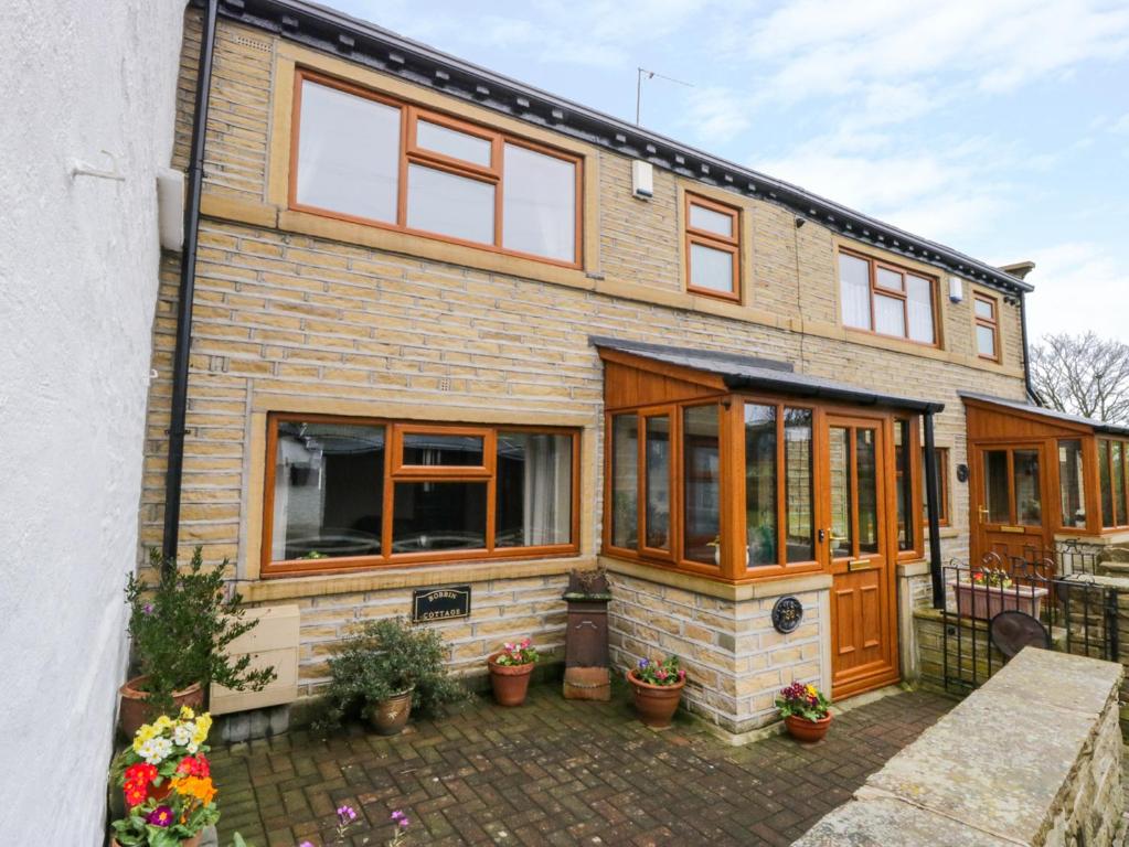 een stenen huis met houten deuren en ramen bij Acorn Cottage in Bradford