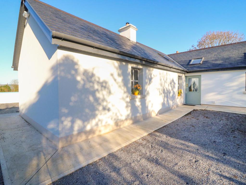 uma casa branca com uma garagem e uma entrada em Longfield Lodge em Killarney