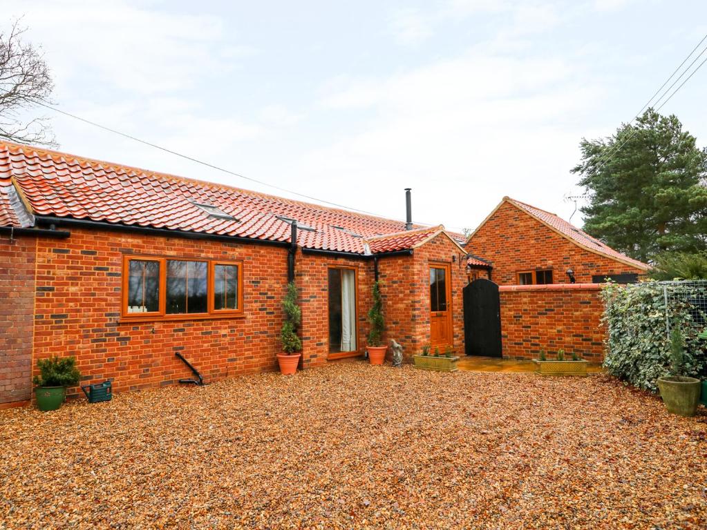 a brick house with a large yard in front of it at Honey Buzzard Barn in Fakenham