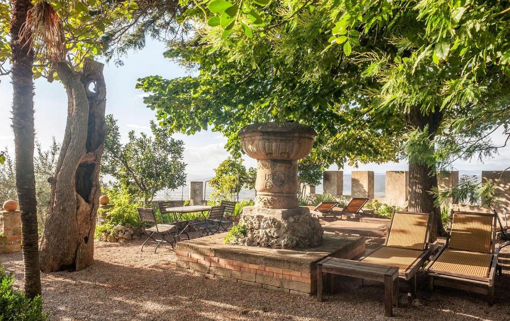 una fontana in un cortile con sedie e alberi di Il Castello Gavorrano a Gavorrano