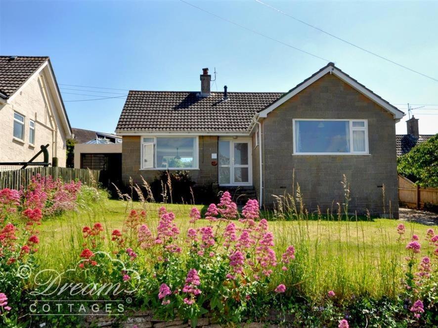 a house with a garden with flowers in the yard at Hillview Bungalow in Burton Bradstock