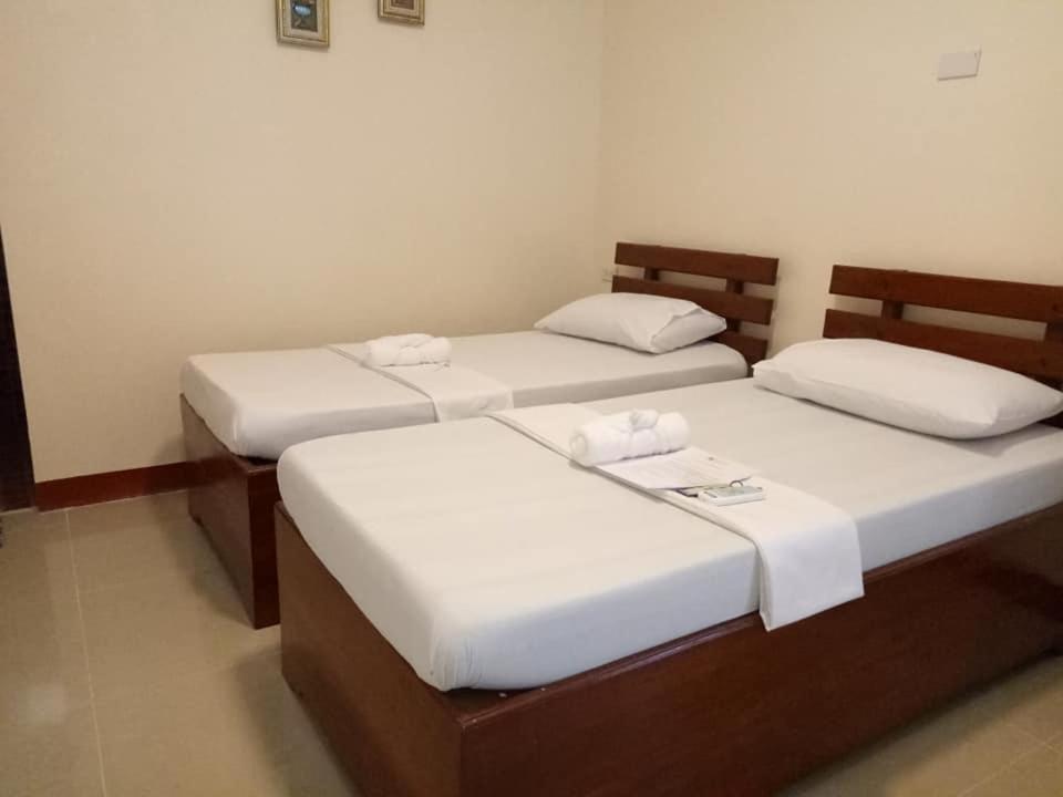 2 bedden in een kamer met witte lakens bij AJ Travellers Inn - Annex in Boracay