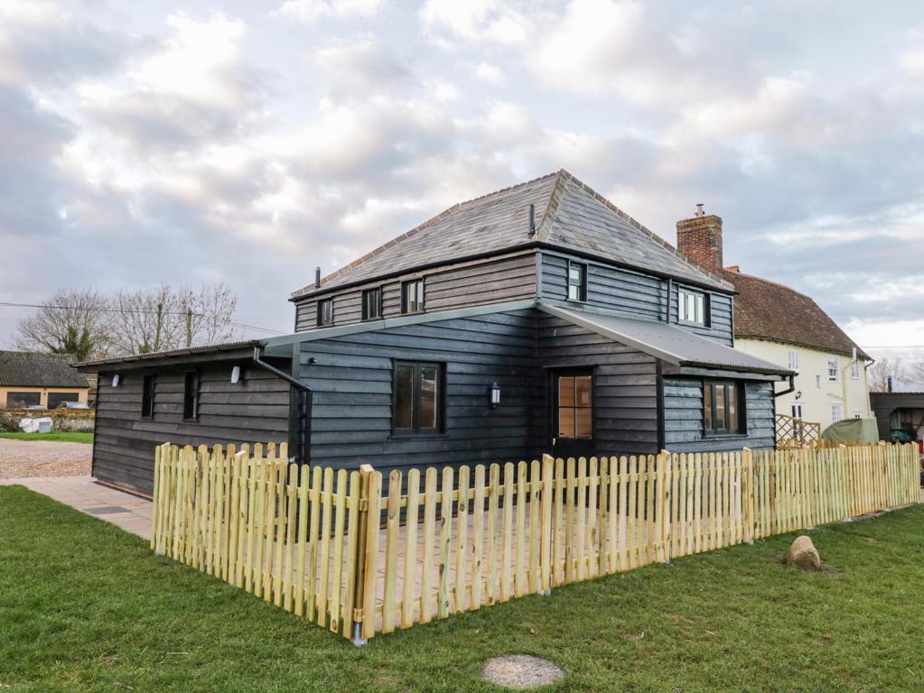 a black house behind a wooden fence at The Granary in Halstead