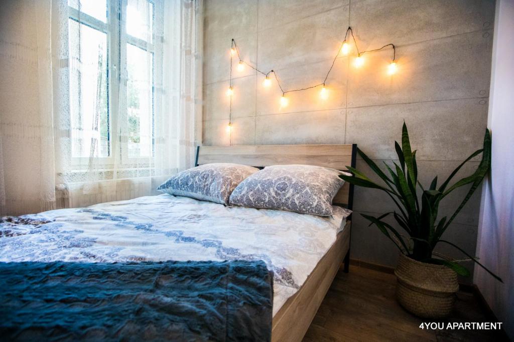 a bedroom with a bed with lights on the wall at 4YOU APARTMENT in Toruń