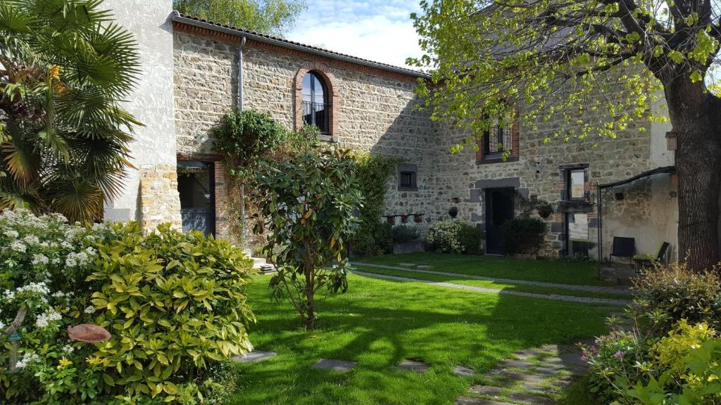 uma antiga casa de pedra com um quintal verde em Altamica em Cournon-dʼAuvergne