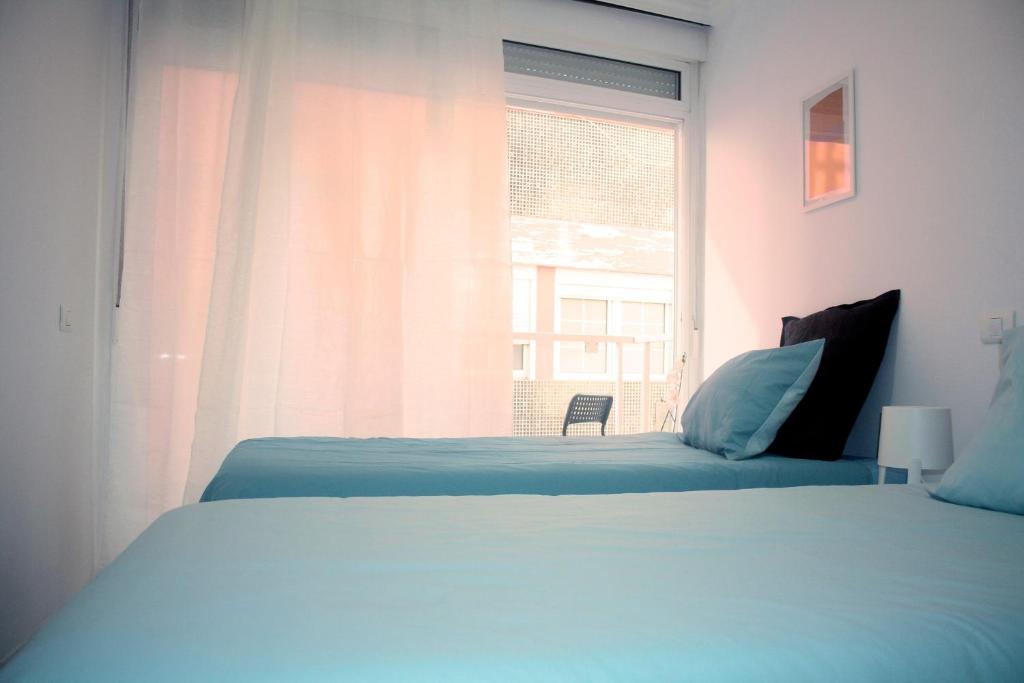 - une chambre avec un lit et une fenêtre avec une chaise dans l'établissement Sagasta Beach Apartment I by Canary365, à Las Palmas de Gran Canaria
