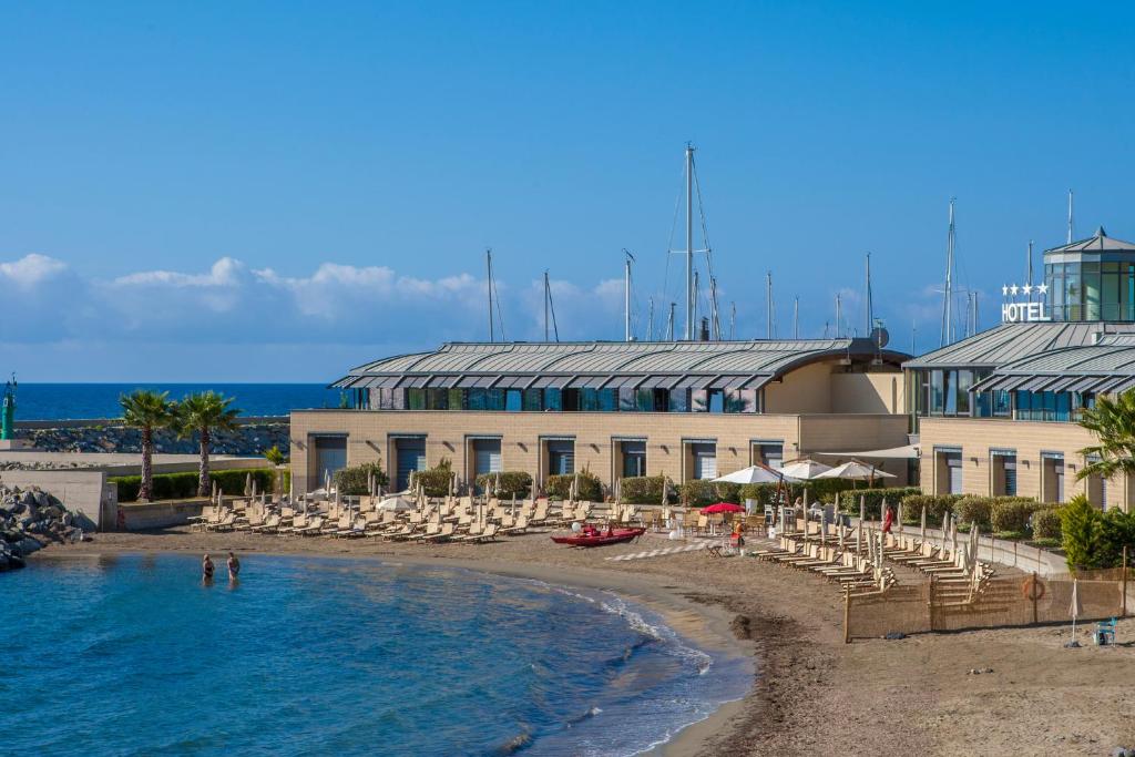 un complejo con piscina, sillas y playa en Hotel Riviera dei Fiori, en San Lorenzo al Mare