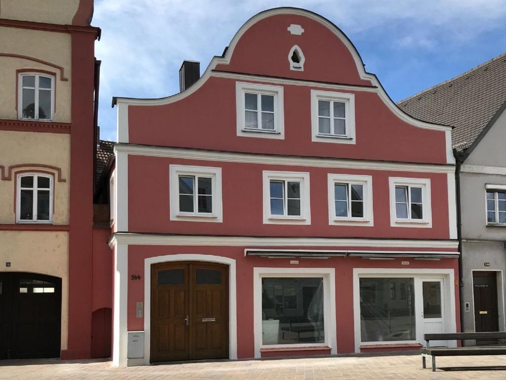 a red and white building with a bench in front of it at Ferienwohnung am Regierungsplatz in Landshut