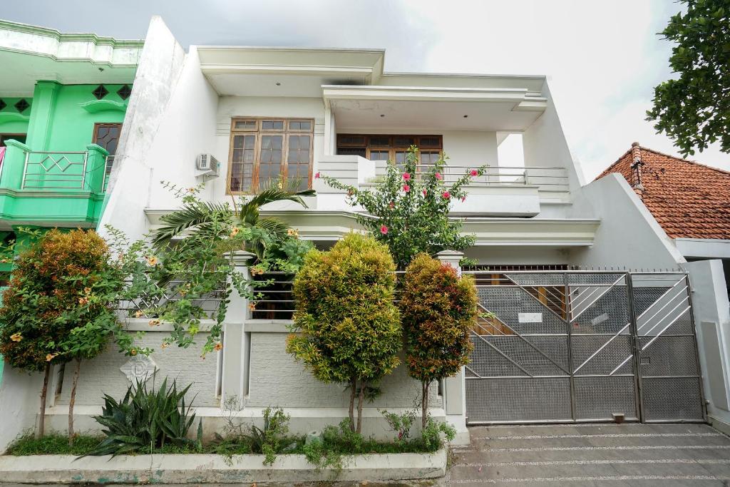 uma casa branca com plantas ao lado dela em Bumi Banyu Bening Syariah by ecommerceloka em Surabaya
