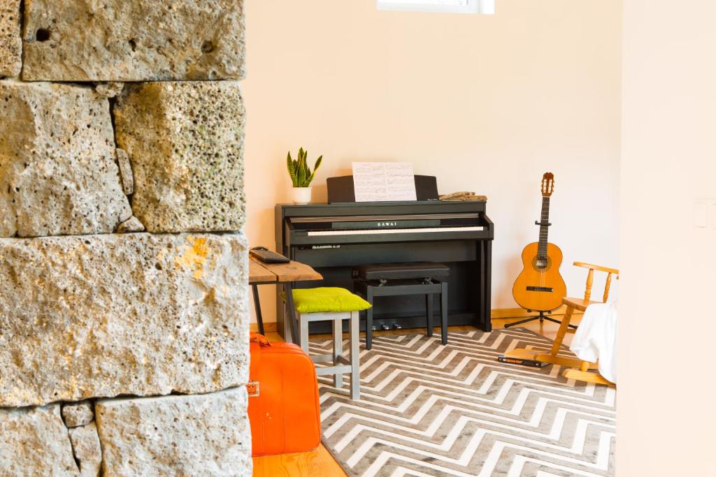 ein Wohnzimmer mit einem Klavier und einer Gitarre in der Unterkunft Casa dos Caldeiras in Lajes do Pico