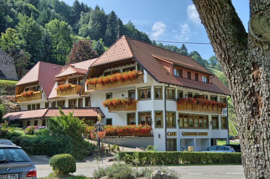 un grande edificio bianco con fiori alle finestre di Gasthaus Sonne a Münstertal/Schwarzwald