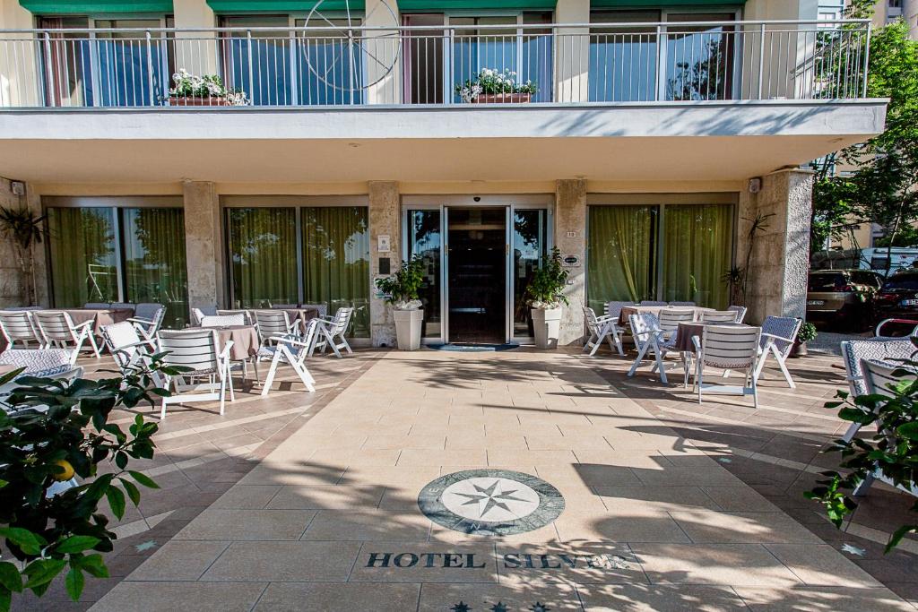 a patio with chairs and tables in front of a building at Hotel Silver in Milano Marittima