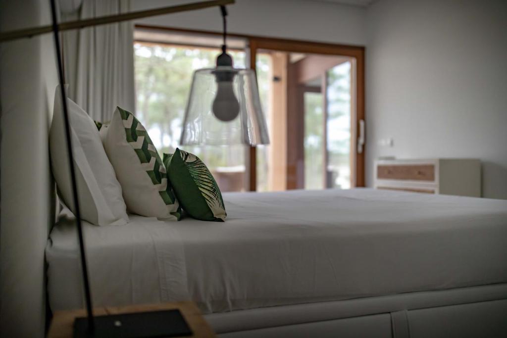 a bed with green and white pillows in a bedroom at Pestana Troia Eco-Resort & Residences in Troia