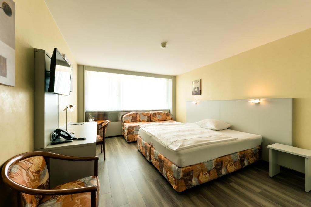 a hotel room with two beds and a window at City Hotel Heilbronn in Heilbronn