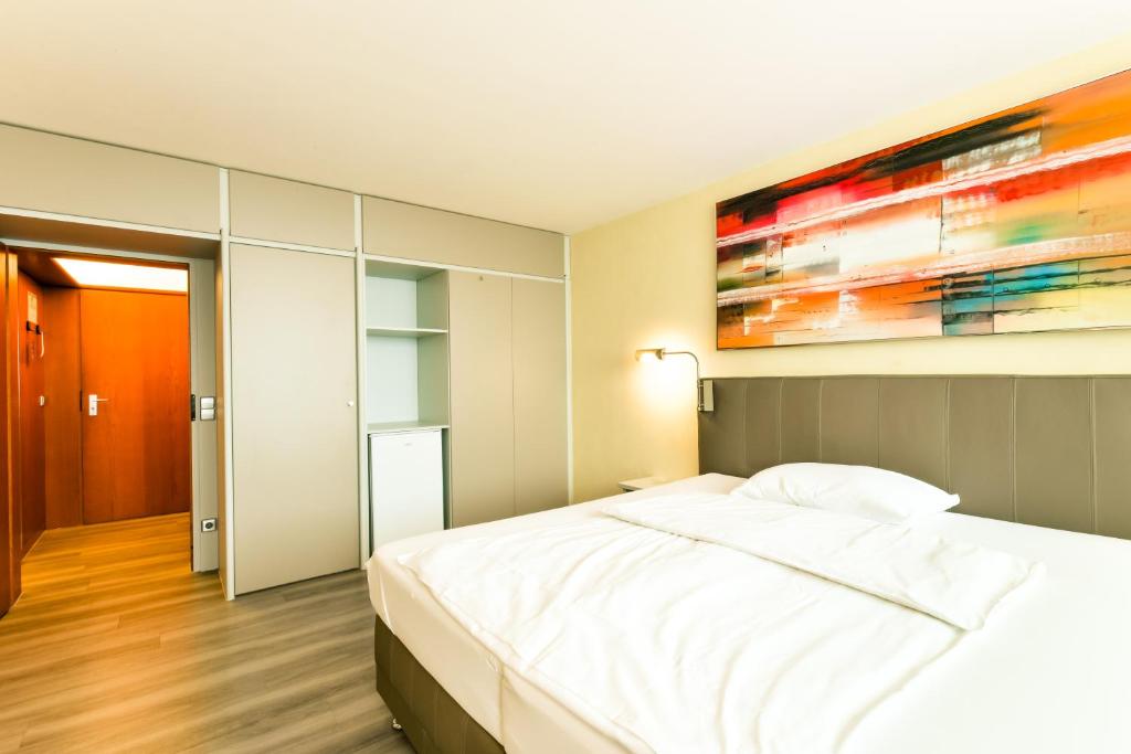 a bedroom with a white bed and a painting on the wall at City Hotel Heilbronn in Heilbronn