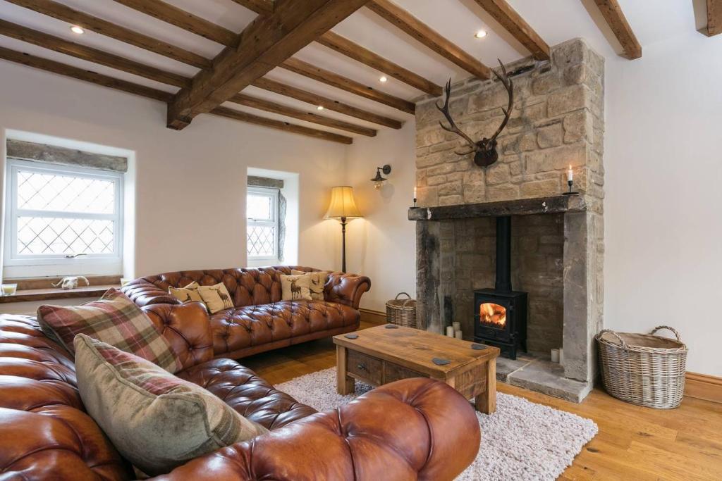 a living room with leather couches and a fireplace at Stunning Blackberry Cottage with Log Burner - located on Haworth Main Street in Haworth