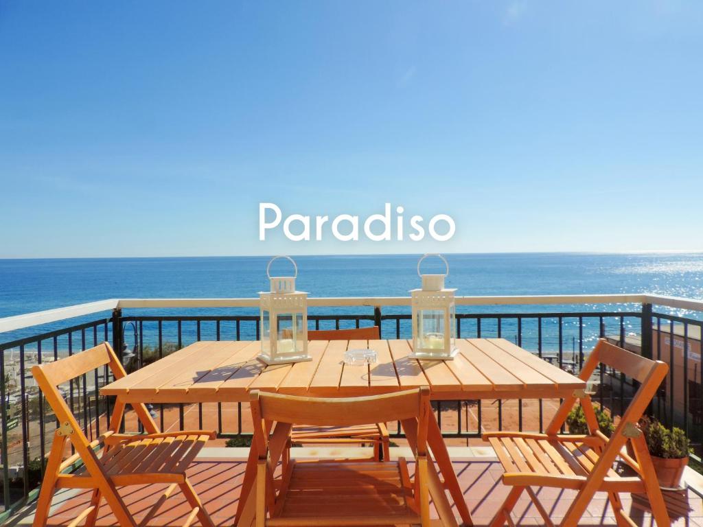 un tavolo in legno con sedie su un balcone con vista sull'oceano di Le Casasse "Paradiso" a Varigotti