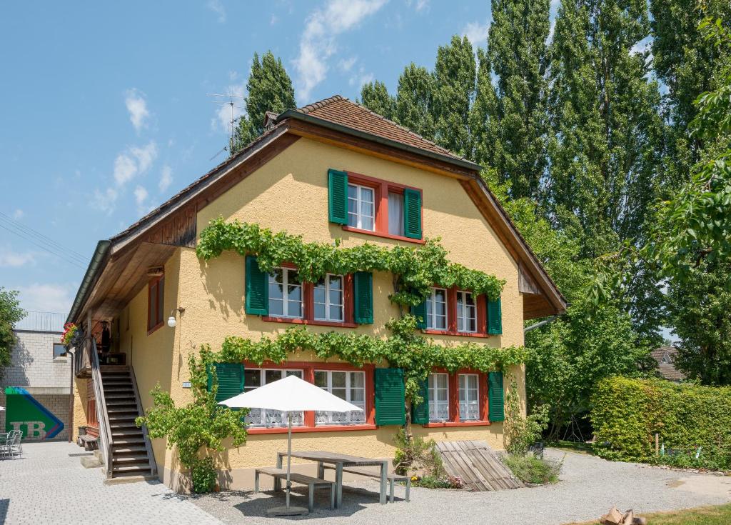 ein Haus mit einem Tisch und einem Sonnenschirm davor in der Unterkunft Beinwil am See Youth Hostel in Beinwil