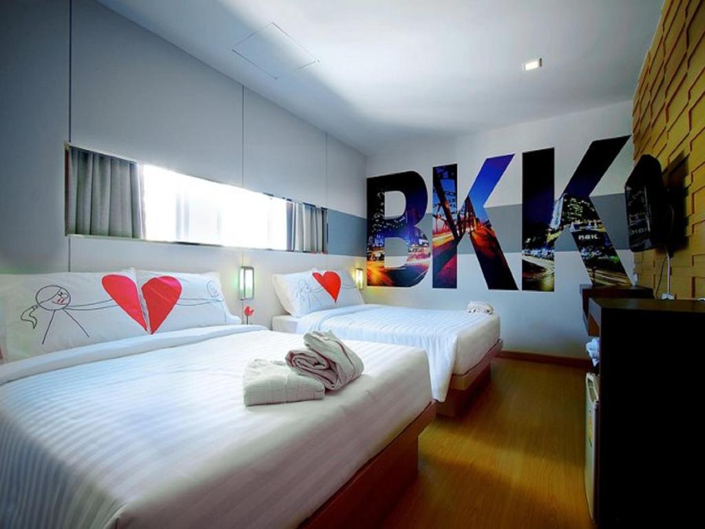 twee bedden in een hotelkamer met posters aan de muur bij Ds67 Suites in Bangkok