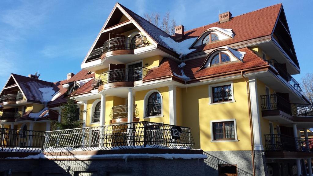 une grande maison jaune avec un toit brun dans l'établissement Apartament Wenecja, à Zakopane