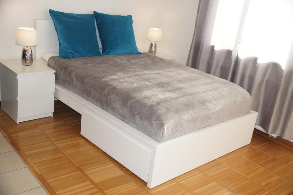 a white bed with blue pillows on top of it at Nadmorski Apartament in Hel